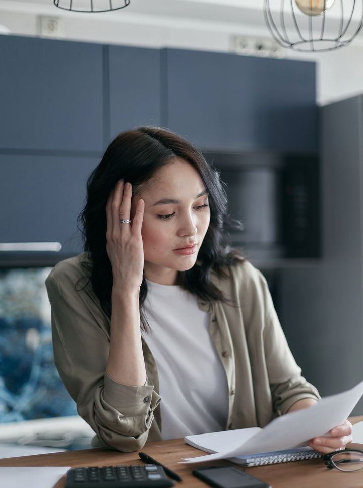 Homeowner at a kitchen table studying a written quote with a calculator