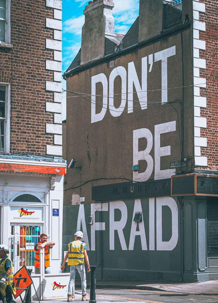 Don't be afraid painted on a gable wall above tradespeople at work
